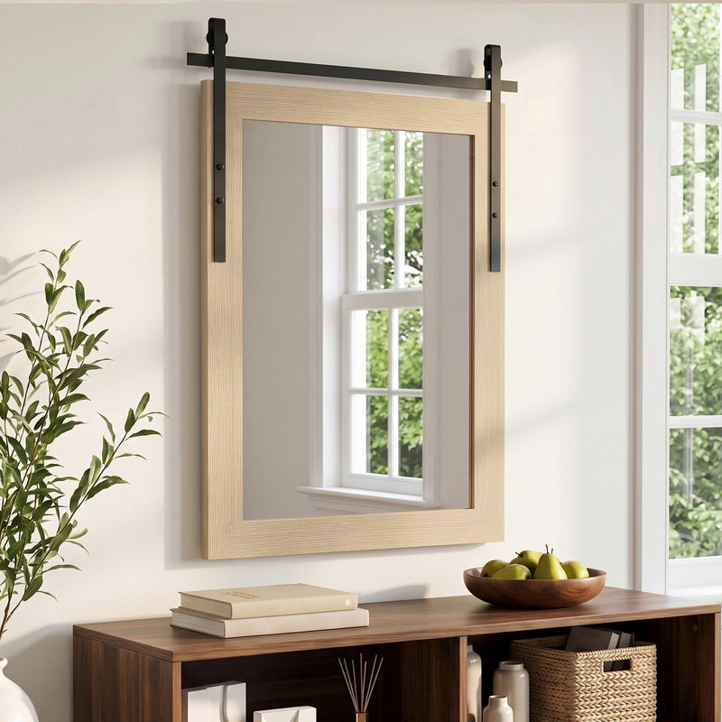 White oak wall mirror above a wooden console with books and a fruit bowl beside a window