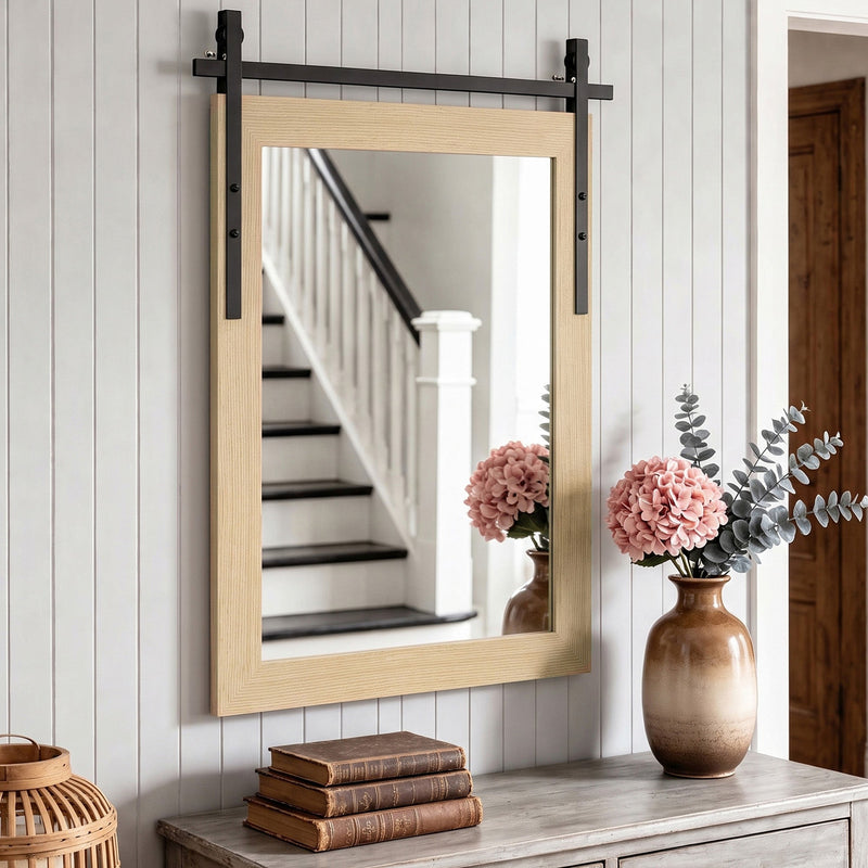 White oak mirror above a hallway console beside a staircase and pink flowers