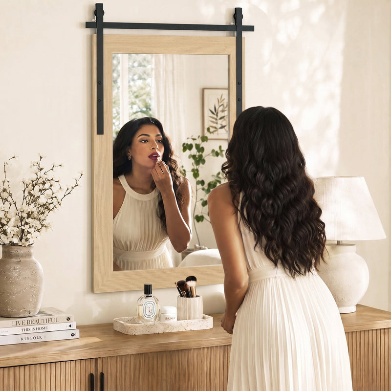 Woman applying lipstick in the white oak mirror above a wooden sideboard
