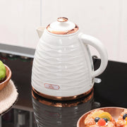 Kettle on a dark gloss worktop next to a fruit bowl and a plate of pastries