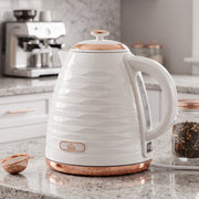 Kettle on a granite worktop with a rose gold tea strainer and loose leaf tea