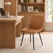 Brown faux leather dining chair used as a home office chair at a wooden desk