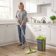 Woman mopping a kitchen floor with the flat mop, bucket standing nearby
