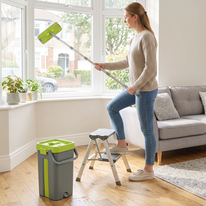Woman cleaning a high window with the long-handled mop, bucket and step stool on the floor
