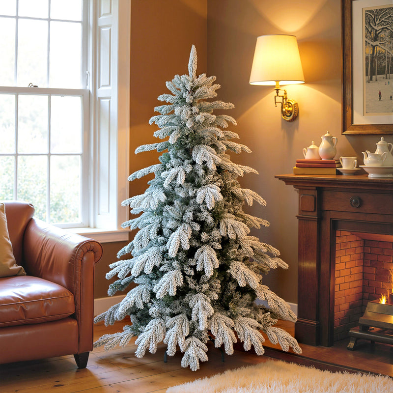 5ft flocked Christmas tree in a cosy living room beside an armchair and fireplace