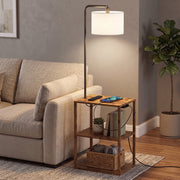 Rustic brown floor lamp with shelf table beside a beige sofa with a phone charging on the top shelf