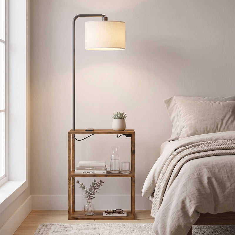Rustic brown floor lamp with shelves beside a bed with a glass of water and books on the shelf