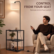 Man in an armchair using the remote beside the black floor lamp with shelves
