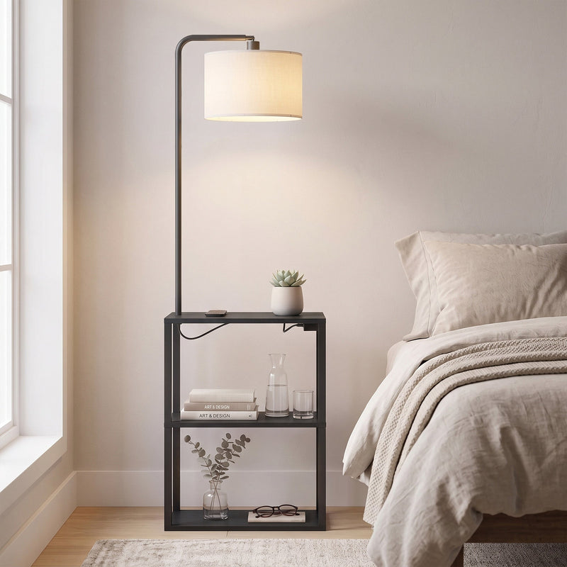 Black floor lamp with shelves beside a bed with a glass of water and books on the shelf