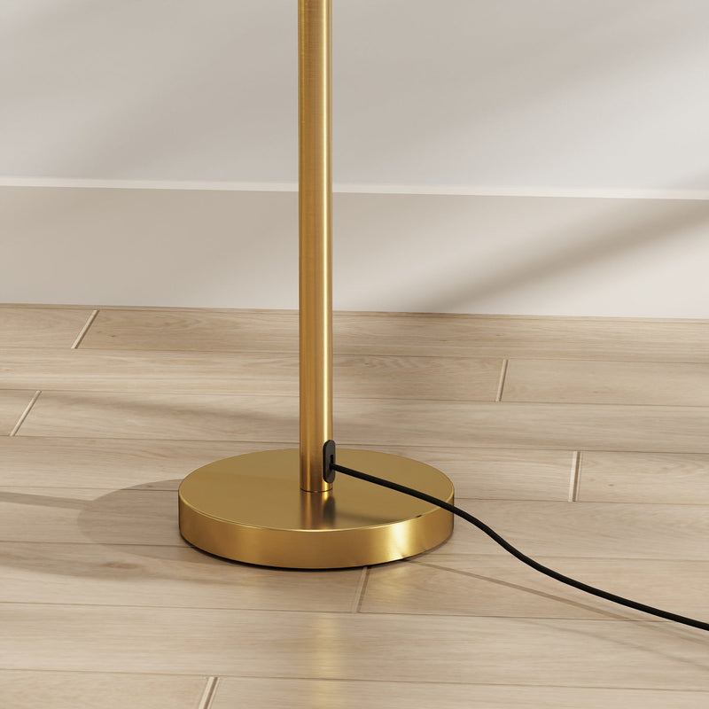 Close-up of the round gold lamp base and black power cord on a wood floor