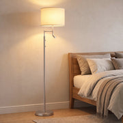 Silver floor lamp glowing beside a bed in a warm bedroom