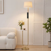 Gold floor lamp with shelf beside a cream armchair and shuttered doors