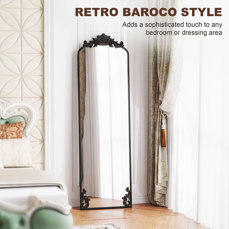 Black baroque floor mirror leaning in a bedroom with a decorative bed and curtains
