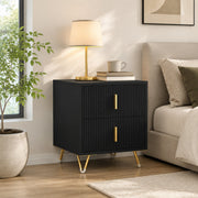 Black and gold-tone fluted bedside table styled beside a bed with lamp and plant