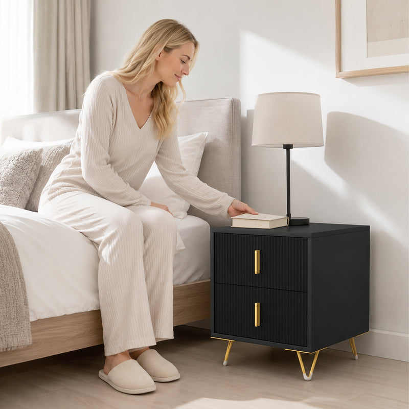 Woman placing a book on the black and gold bedside table next to her bed