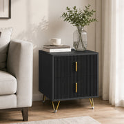 Black bedside table with gold-tone legs styled in a living room with a plant