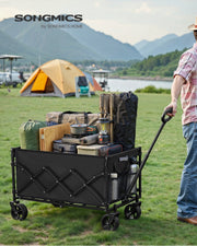 Ink Black camping cart loaded with camping kit being pulled across grass at a lakeside campsite