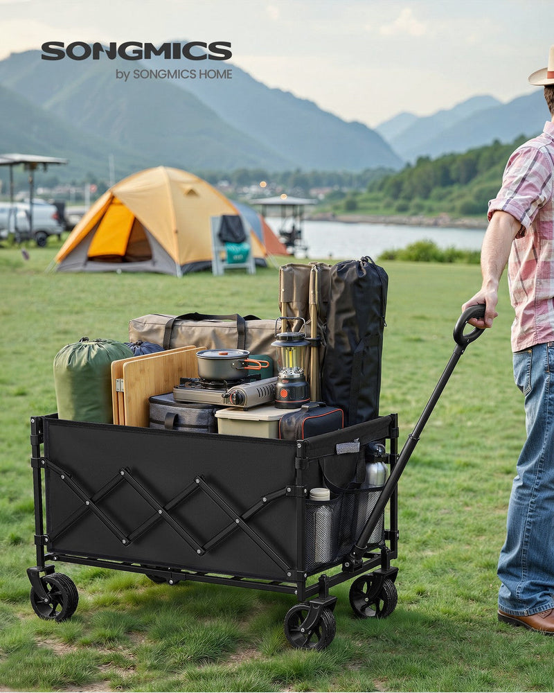 Ink Black camping cart loaded with camping kit being pulled across grass at a lakeside campsite