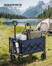 Midnight blue camping cart packed with a cooler and gear beside a lake with a tent in the background
