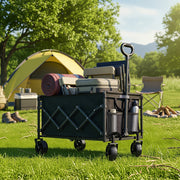 Folding wagon full of camping gear and a rolled mat on grass beside a yellow tent