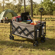Camping trolley loaded with a cool box, firewood and camp chairs among trees at a campsite