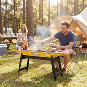 Yellow Outsunny charcoal BBQ grill set up at a campsite with a family grilling food