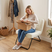Woman opening the delivery box while sitting on the cream white accent chair