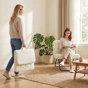 Woman carrying the folded cream white accent chair past a reader seated on another