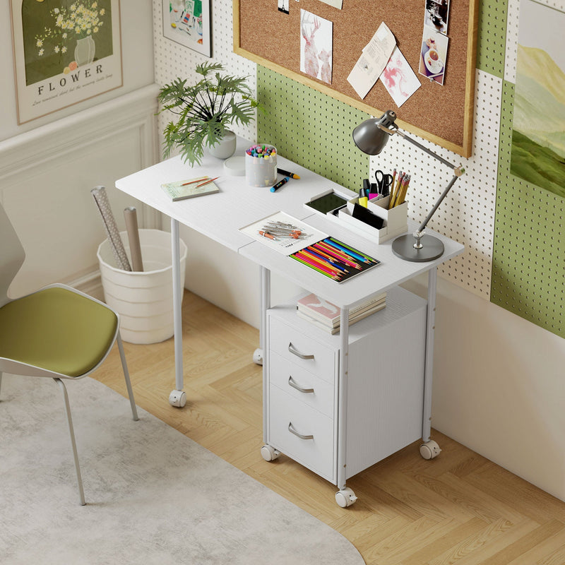 White foldable desk set up as a craft and study desk with pencils, a lamp and a pinboard