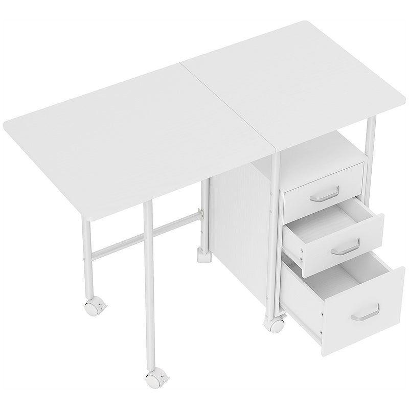 White foldable computer desk with an extended tabletop and 3 drawers on wheels, one drawer open, seen from above
