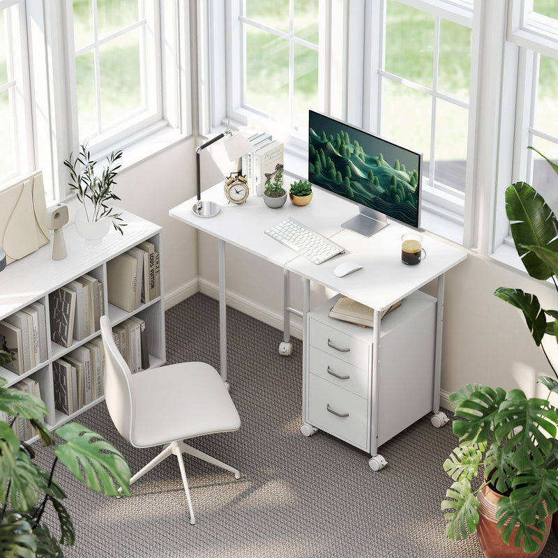 White foldable desk with a monitor and keyboard in a bright room by a window with a white chair