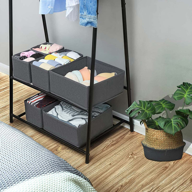 Grey drawer organiser boxes on the shelves of a black clothes rack in a bedroom