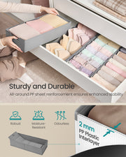 Grey fabric drawer organiser fitted inside a wardrobe drawer with folded clothes
