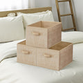 3 sand beige storage bins stacked on a white bed beside a wooden ladder