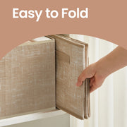 A hand holding one storage bin folded flat for storage