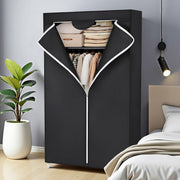 Black fabric wardrobe in a bedroom beside a plant and pendant light