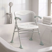 Shower chair placed inside a bathtub beside a shower head and folded towels