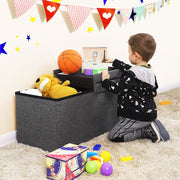 Child kneeling at the dark grey ottoman in a playroom lifting out toys