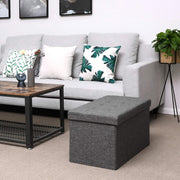 Closed dark grey ottoman used as a footstool beside a sofa and coffee table