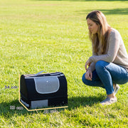 Black travel cat litter box on grass beside a woman with 43 x 33 x 34 cm dimensions marked