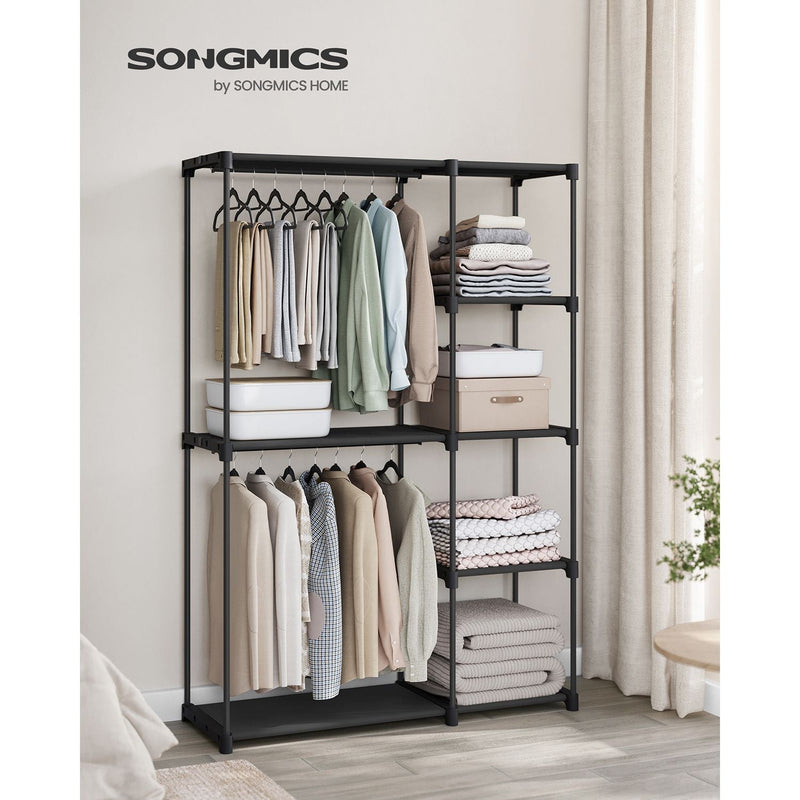 Black wardrobe styled in a bedroom with hanging clothes and folded towels on the shelves