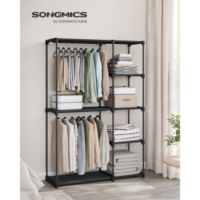 Black wardrobe styled in a bedroom with hanging clothes and folded towels on the shelves