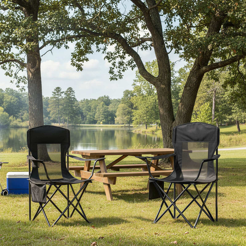 Two ink black camping chairs beside a wooden picnic table and cool box