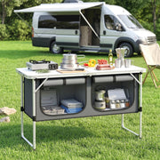 Camping cupboard set up beside a campervan with cooking pot, stove and vegetables on top