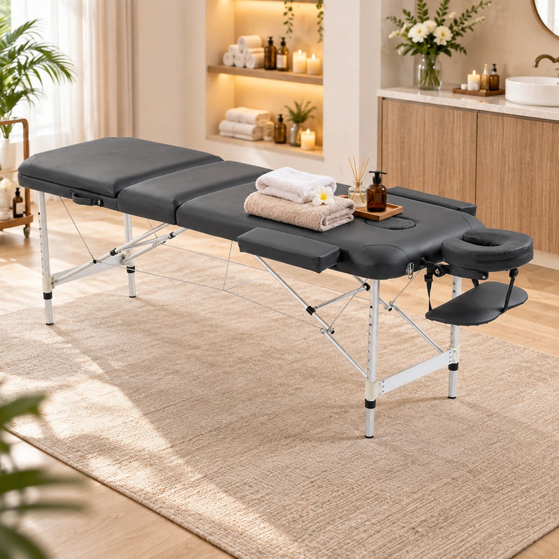 Black massage table set up in a spa-style room with towels and oils