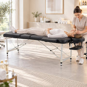 Client lying flat on the black massage table with a therapist at the head end