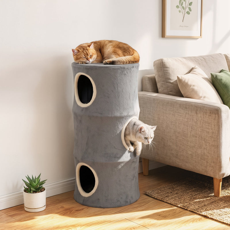 Cat napping on the top perch of the cat tower while another cat climbs out of a middle door