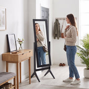 Freestanding mirror styled in a hallway entryway with coat hooks
