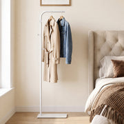 White clothes rail with a coat and denim jacket in a bedroom beside a bed