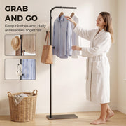 Woman taking a shirt from the black clothes rail, with close-ups of the hooks holding a hat and bag